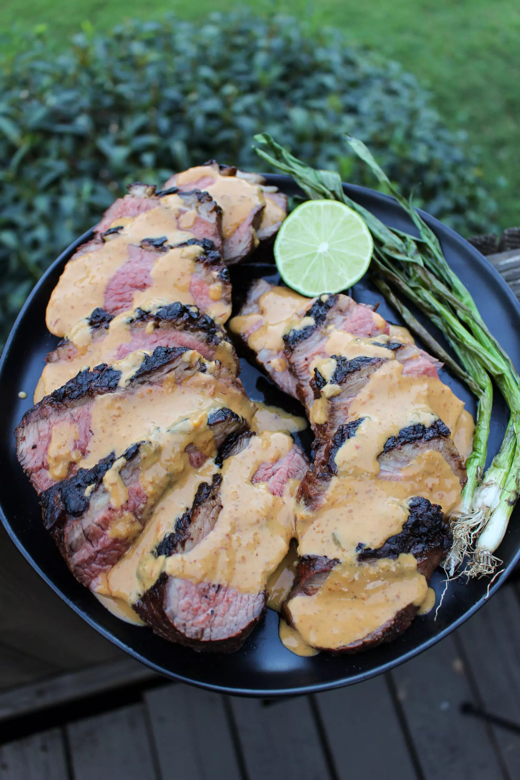 Bistec a la parrilla con salsa de mantequilla de maní con la salsa rociada.