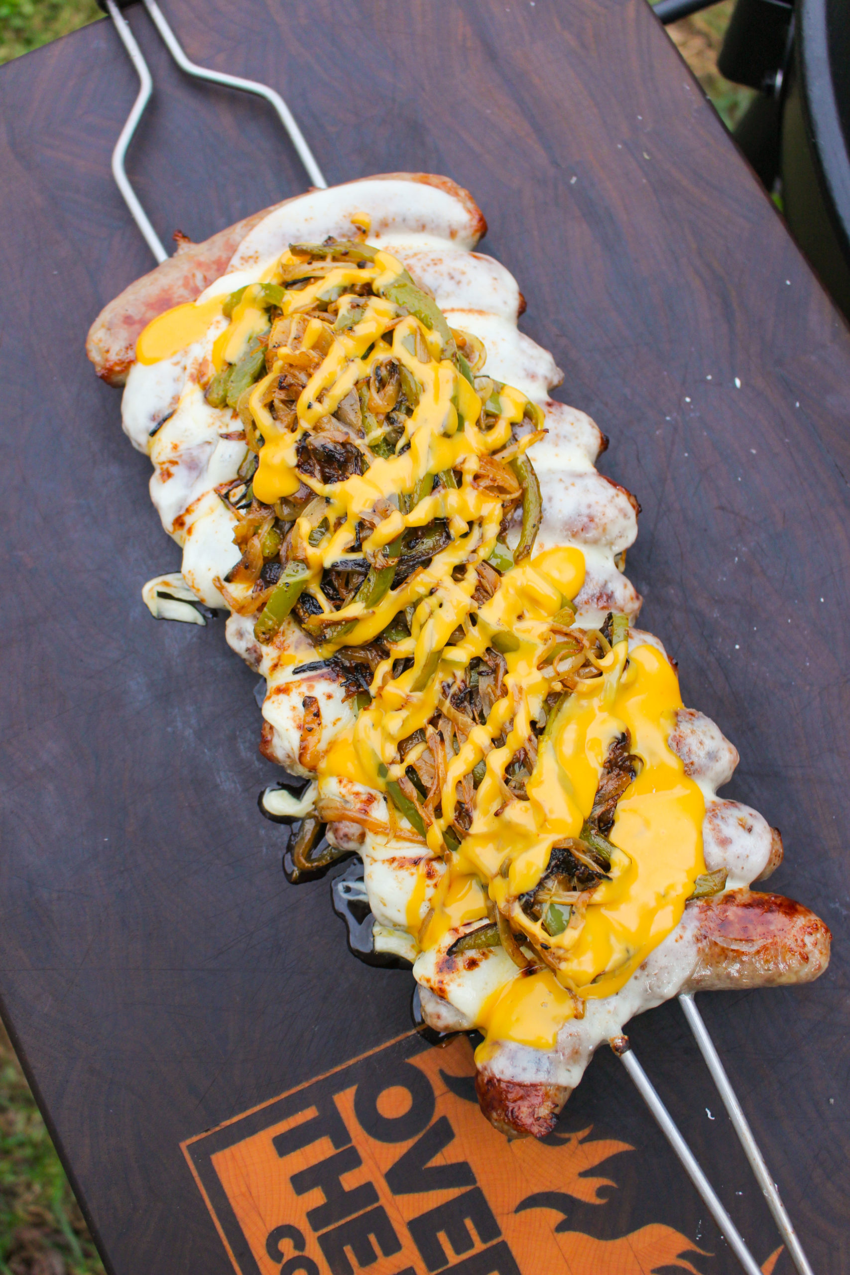 Brochetas de salchicha de queso Philly terminadas y en la tabla de cortar.